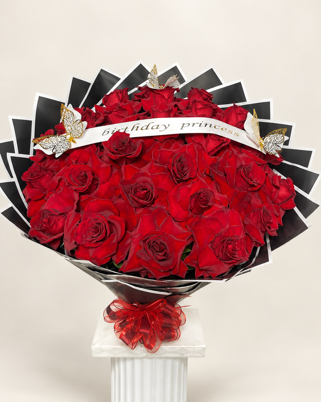 Arreglo floral 19: rosas rojas envueltas en papel negro y blanco con listón «birthday princess»
