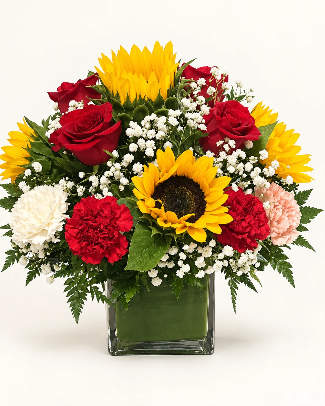 Arreglo floral con girasoles, rosas rojas, claveles y gypsophila en florero cuadrado