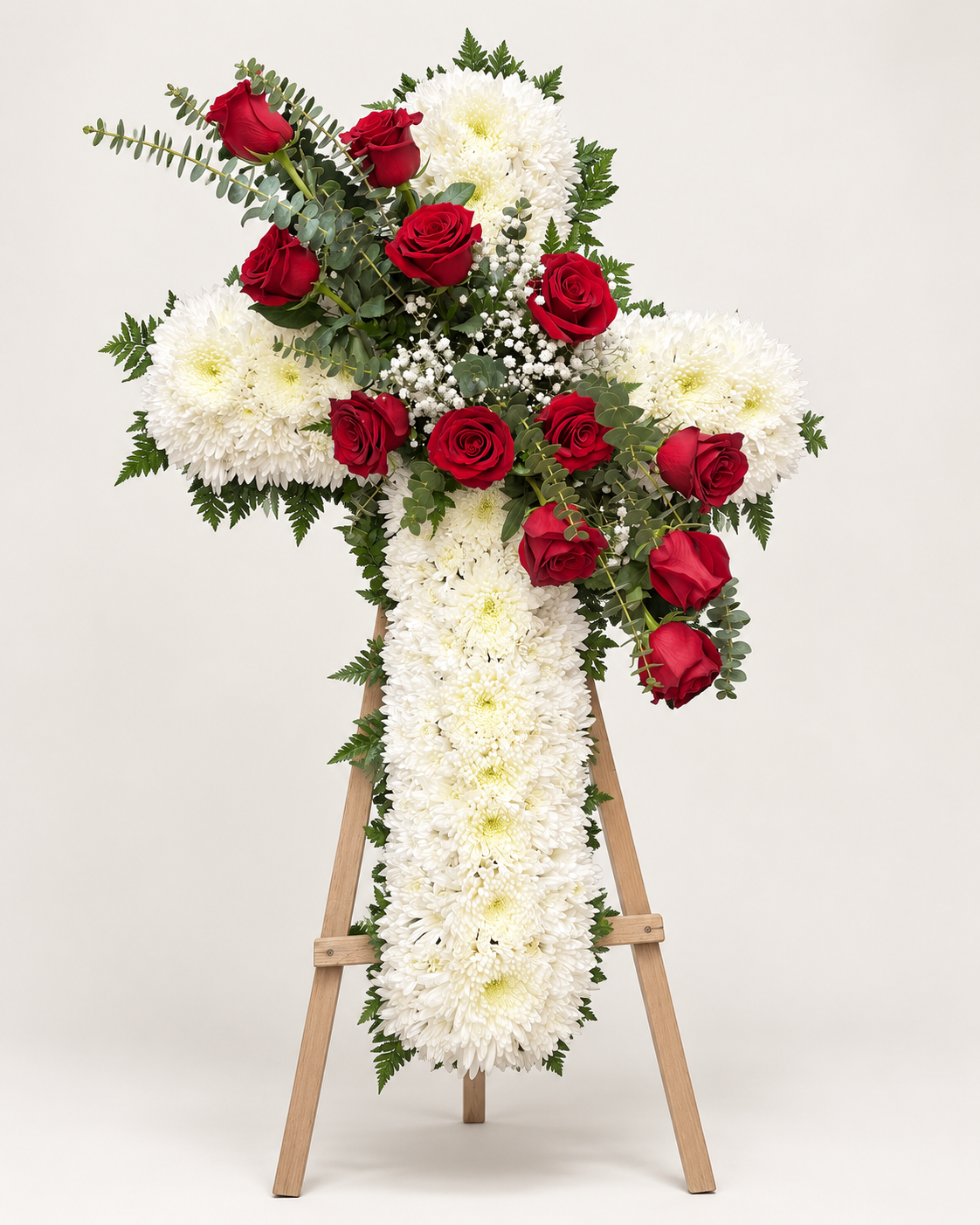 Arreglo fúnebre 2: cruz fúnebre de crisantemos blancos con rosas rojas y eucalipto sobre atril