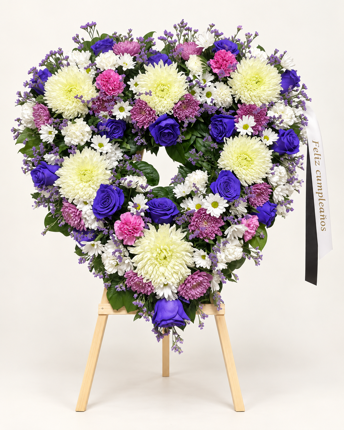 Arreglo fúnebre 3: corona en forma de corazón con rosas azules, crisantemos blancos y claveles rosados sobre atril