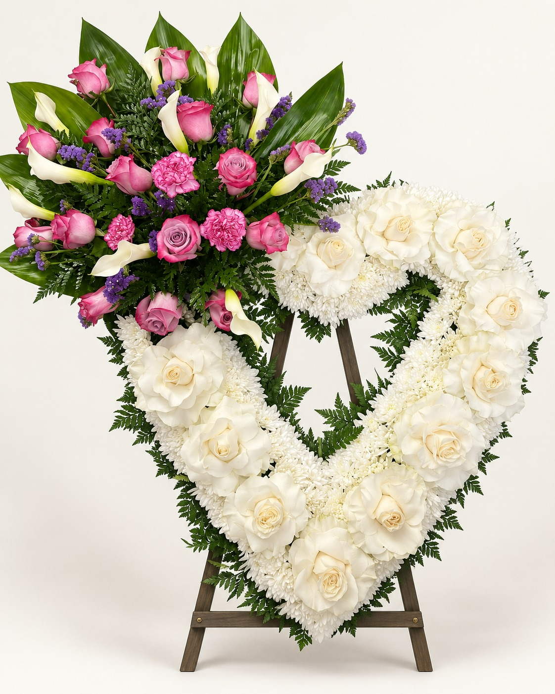 Corazón floral blanco con rosas y flores rosadas sobre atril